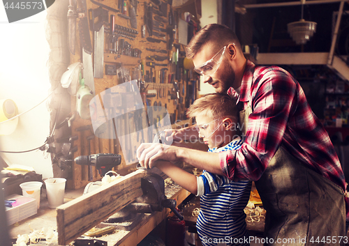 Image of father and son with plane shaving wood at workshop