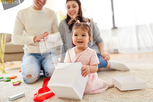 Image of baby girl with birthday gift and parents at home