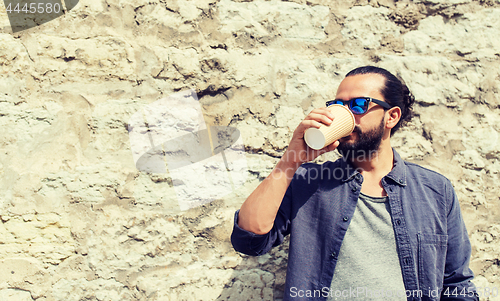 Image of man drinking coffee from paper cup on street