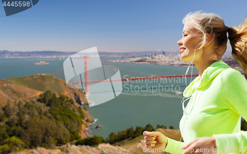 Image of woman with earphones running over san francisco