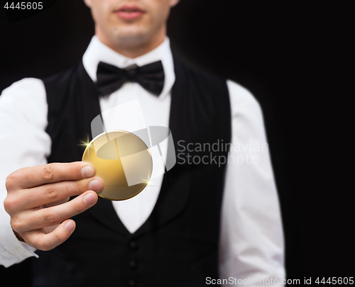 Image of close up of casino dealer holding golden coin