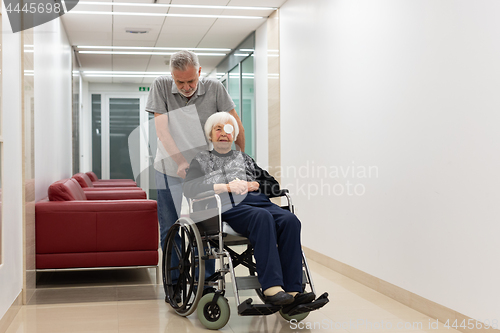 Image of Middle aged man helping and taking to elderly 95 years old woman sitting in the wheelchair.