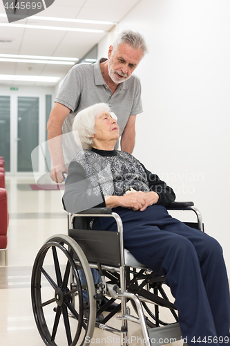 Image of Middle aged man helping and taking to elderly 95 years old woman sitting in the wheelchair.