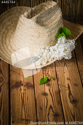 Image of Still-life with a bouquet of lilacs and a straw hat, close-up
