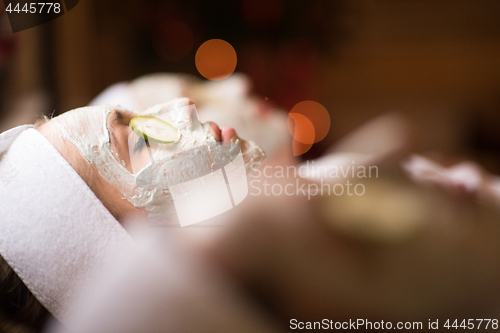 Image of woman is getting facial clay mask at spa