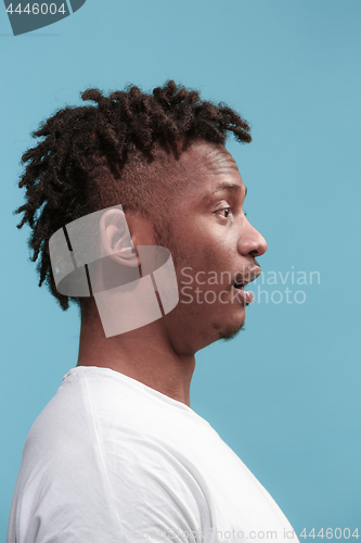 Image of The surprised business Afro-American man standing and looking blue background. Profile view.