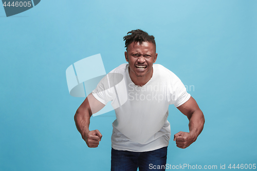 Image of The young emotional angry afro man screaming on blue studio background