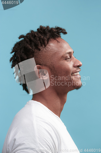 Image of The happy business Afro-American man standing and smiling against blue background. Profile view.