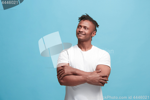 Image of The happy business afro-american man standing and smiling against blue background.