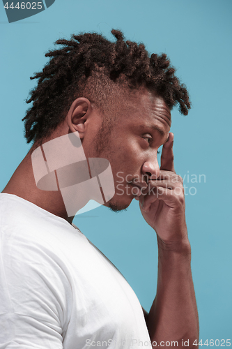 Image of Let me think. Doubtful pensive Afro-American man with thoughtful expression making choice against blue background