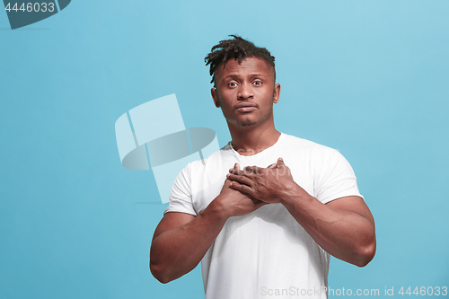 Image of The happy business afro-american man standing and smiling against blue background.