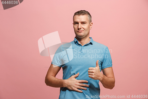 Image of The happy business man standing and smiling against pink background.