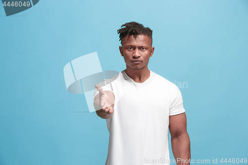Image of The overbearing afro-american businessman point you and want you, half length closeup portrait on blue background.