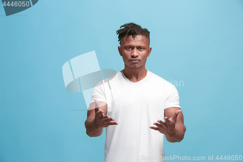 Image of Beautiful male half-length portrait isolated on blue studio backgroud. The young emotional surprised man