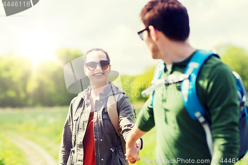 Image of happy couple with backpacks hiking outdoors