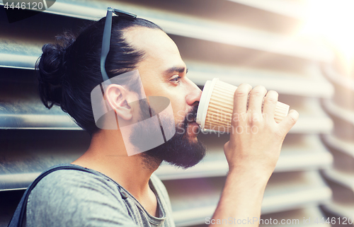 Image of man drinking coffee from paper cup on street