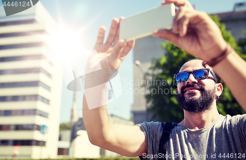 Image of man taking video or selfie by smartphone in city