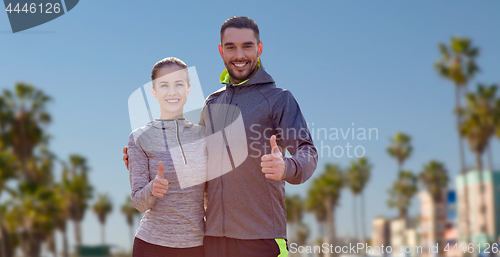 Image of smiling couple in sport clothes showing thumbs up