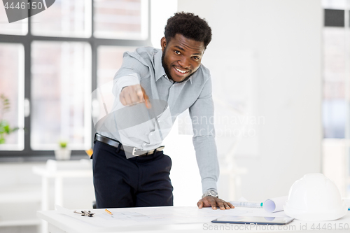 Image of african architect with blueprint pointing at you