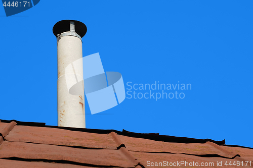 Image of Old chimney of asbestos pipe over a rusty metal roof 