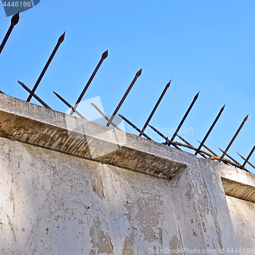 Image of Old concrete fence with two-sided acute iron pins