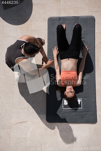 Image of woman with personal trainer doing morning yoga exercises top vie