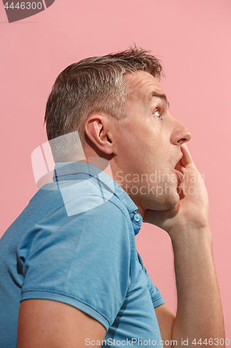 Image of The young attractive man looking suprised isolated on pink