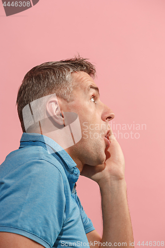 Image of The young attractive man looking suprised isolated on pink