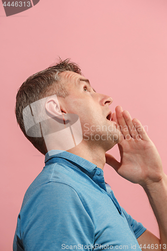 Image of The young man whispering a secret behind her hand over pink background