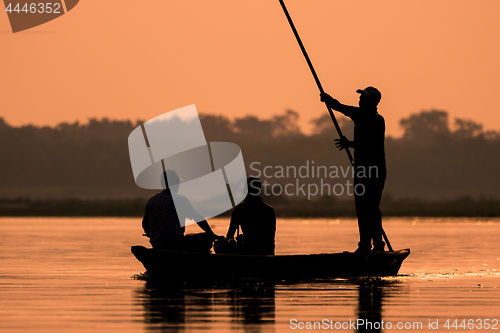 Image of Men in a boat on a river silhouette