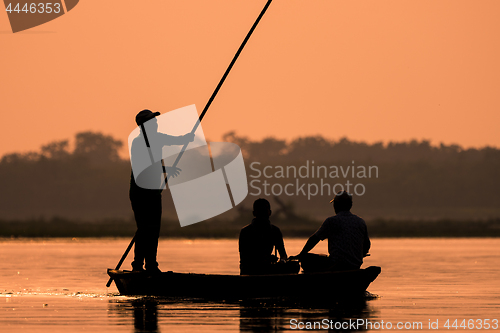 Image of Men in a boat on a river silhouette