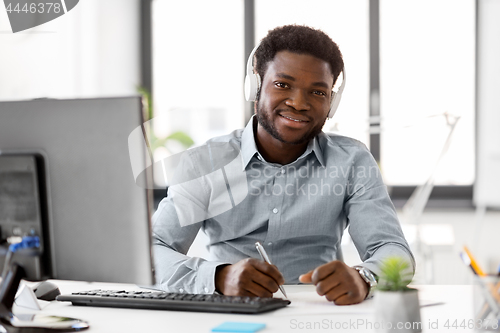 Image of businessman with headphones and papers at office