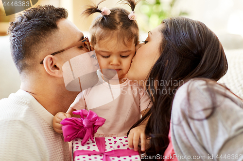 Image of parents kissing little daughter with birthday gift