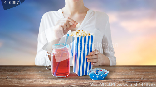 Image of woman eating popcorn with drink in glass mason jar