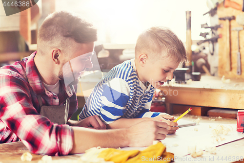 Image of happy father and son with blueprint at workshop