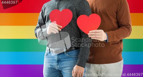 Image of close up of happy male couple holding red hearts