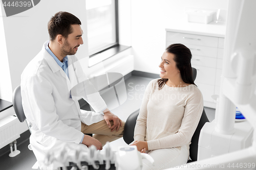 Image of dentist talking to female patient at dental clinic