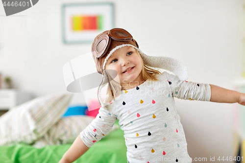 Image of happy little girl in pilot hat playing at home