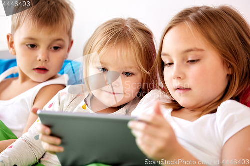 Image of little kids with tablet pc in bed at home