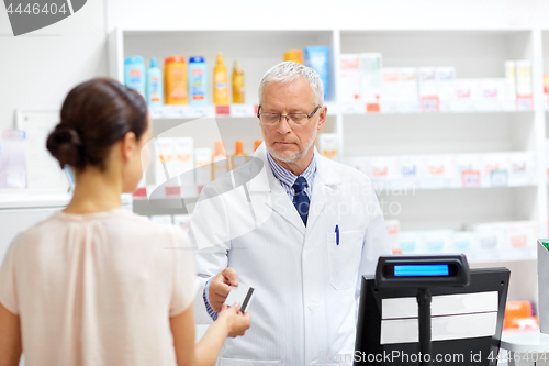 Image of apothecary taking customer credit card at pharmacy