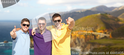 Image of group of male friends hugging over big sur coast