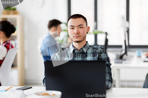 Image of creative man with laptop working at office