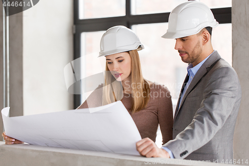 Image of architects with blueprint and helmets at office