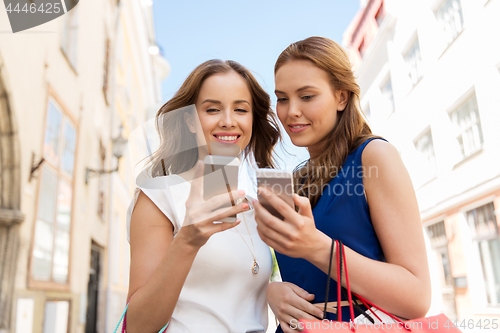 Image of happy women with shopping bags and smartphones