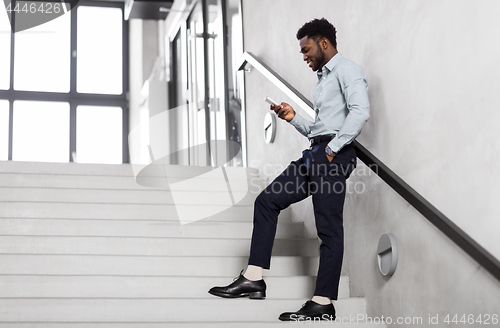 Image of businessman with smartphone at office stairs