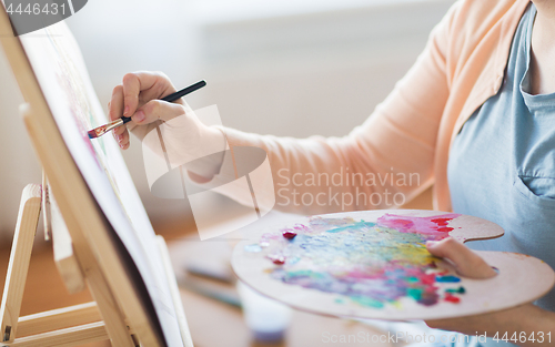 Image of artist with palette and brush painting at studio