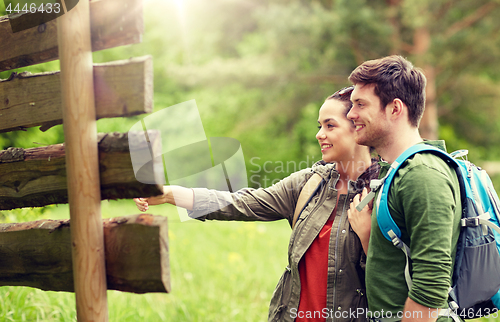 Image of smiling couple at signpost with backpacks hiking