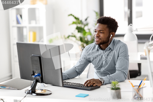 Image of businessman with earphones and computer at office