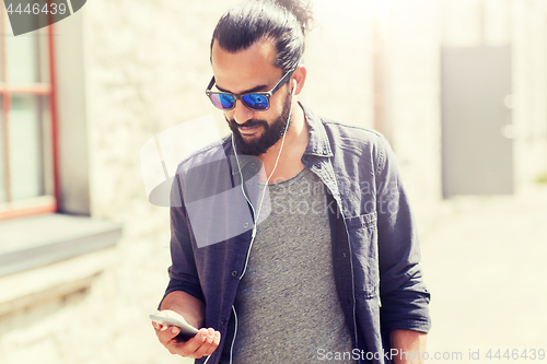 Image of man with earphones and smartphone walking in city