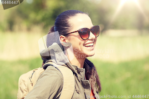 Image of happy young woman with backpack hiking outdoors